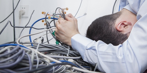 Frustrated man lying down trying to figure out and sort  computer cables